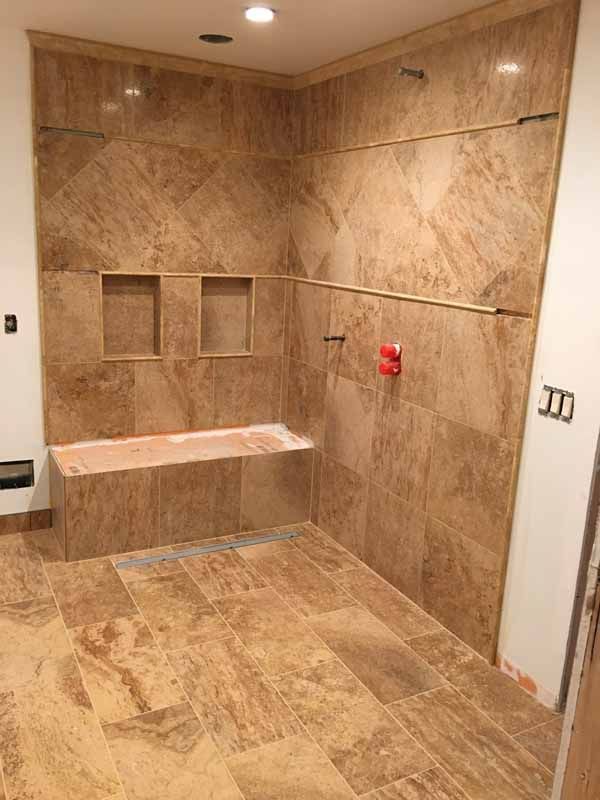 A bathroom with a tub , shower and tiled walls.