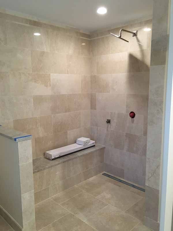 A bathroom with a walk in shower and a bench.