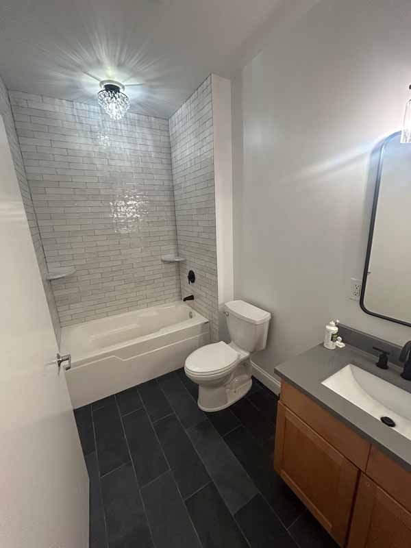 A bathroom with a toilet , sink , bathtub and mirror.