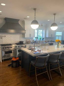 A kitchen with a large island , stove , sink and chairs.