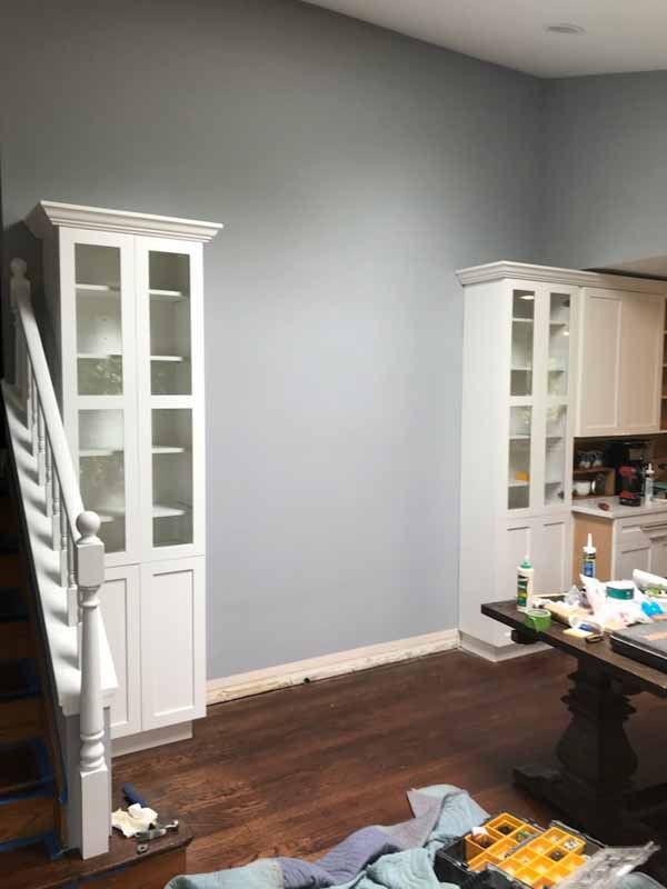A living room with a table , cabinets , and stairs.