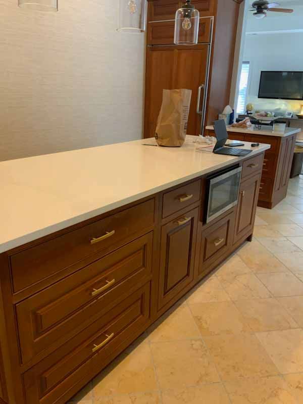 A kitchen with wooden cabinets and a large island with a white counter top.