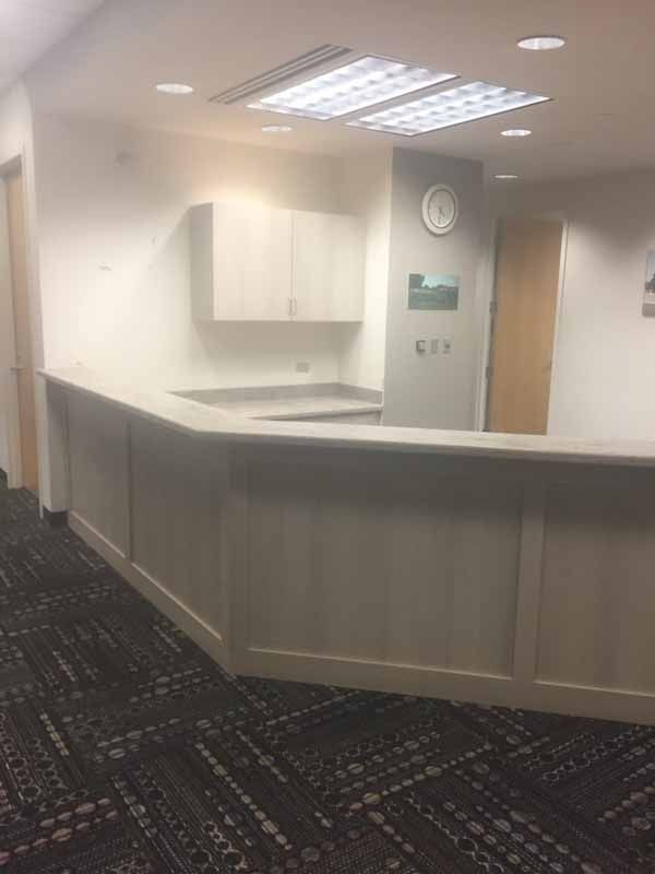 A reception desk in an office with a clock on the wall.