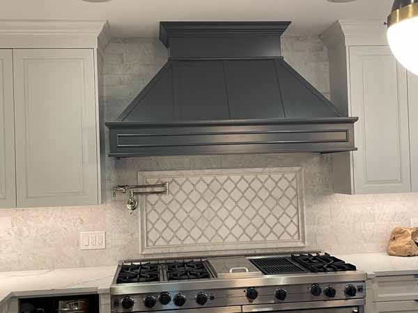 A kitchen with a stove and a hood above it.