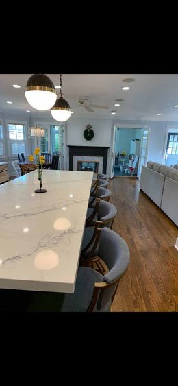 A kitchen with a large island , chairs and a fireplace.