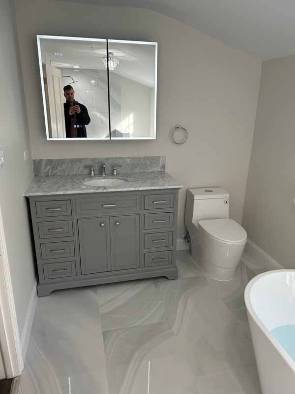 A bathroom with a sink , toilet , mirror and bathtub.