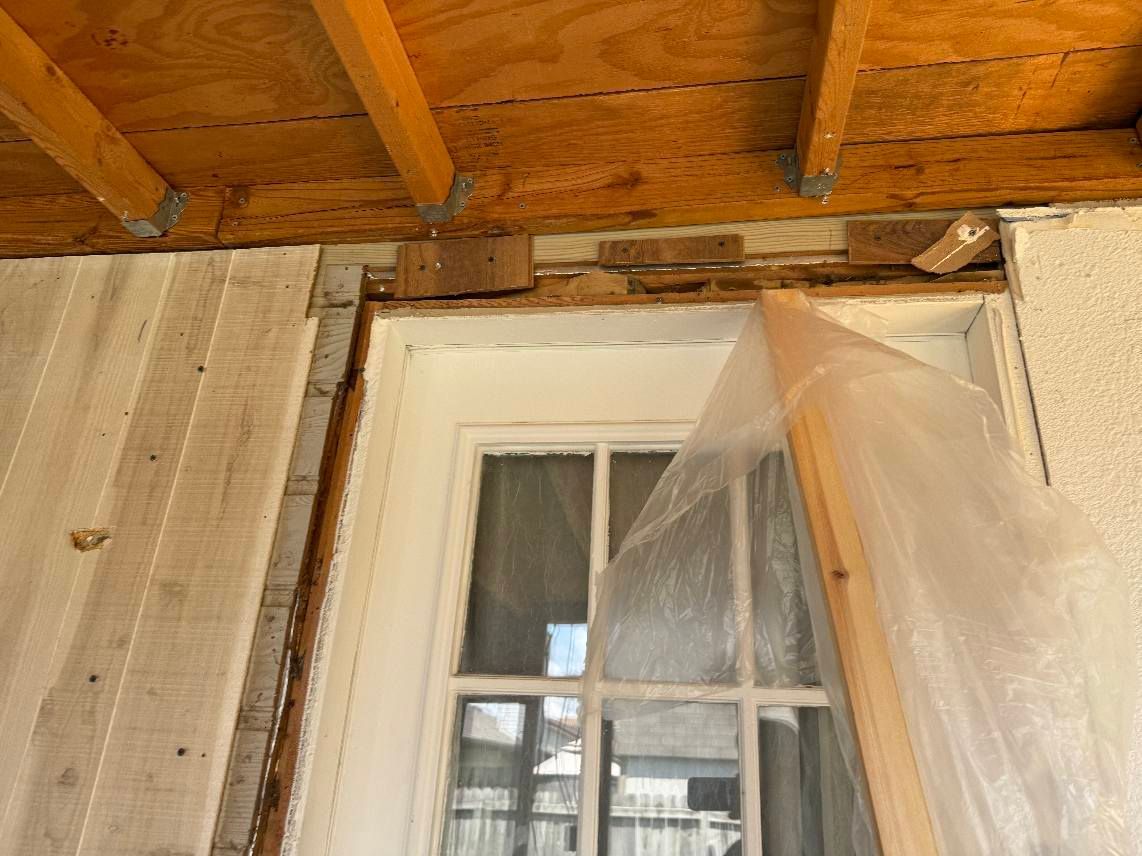A door is being removed from a house and covered in plastic.