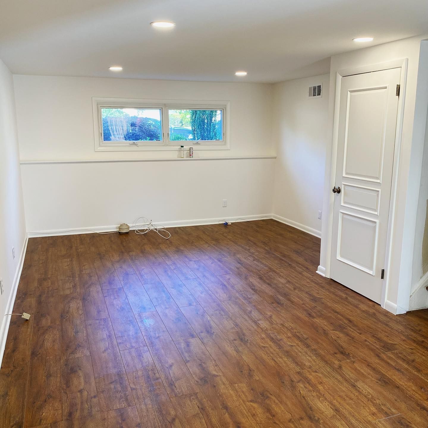 An empty room with hardwood floors and white walls