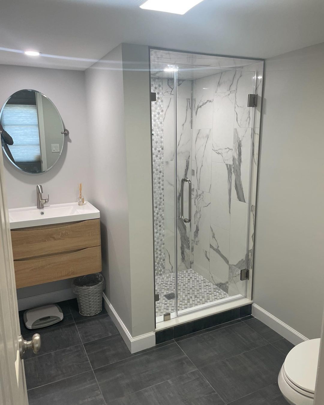 A bathroom with a walk in shower a sink and a toilet