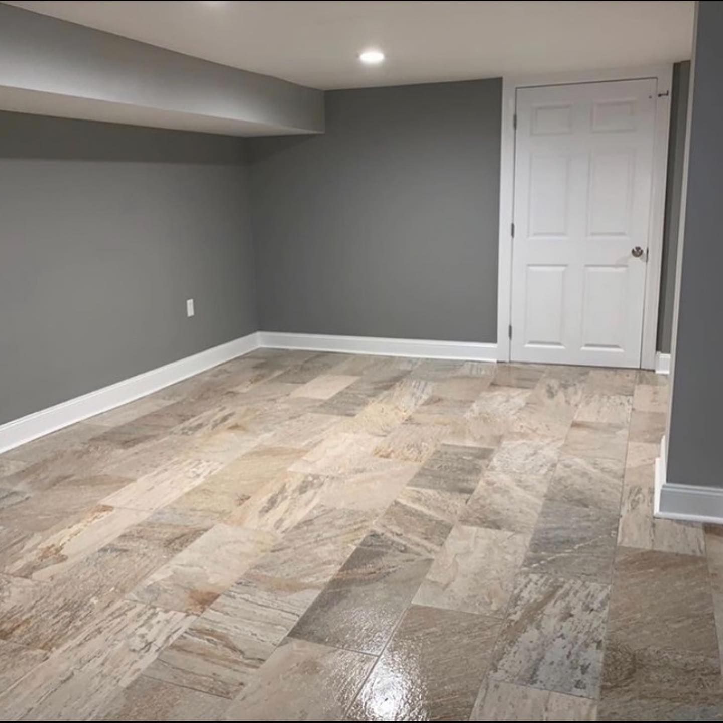 An empty room with a tiled floor and gray walls.