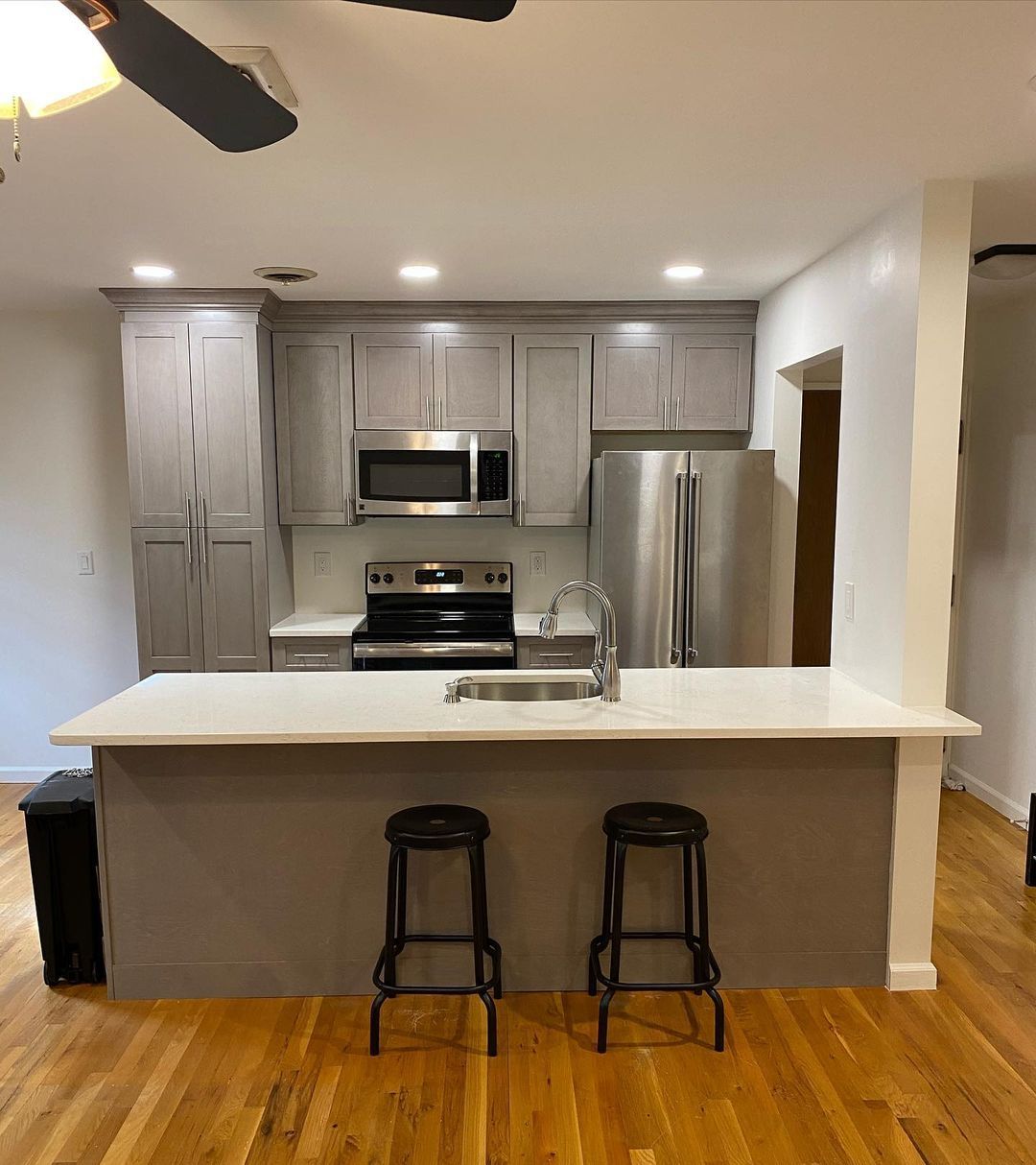 A kitchen with stools and a ceiling fan