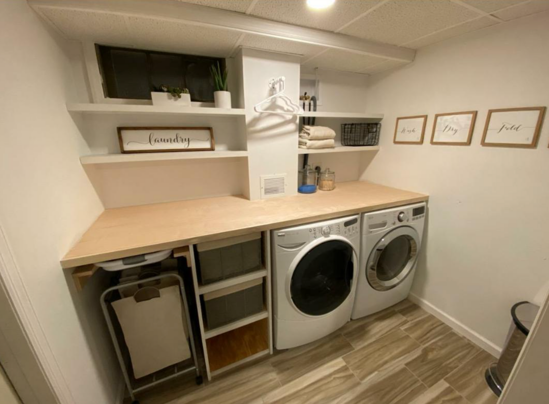 A laundry room with a washer and dryer and a wooden counter top.