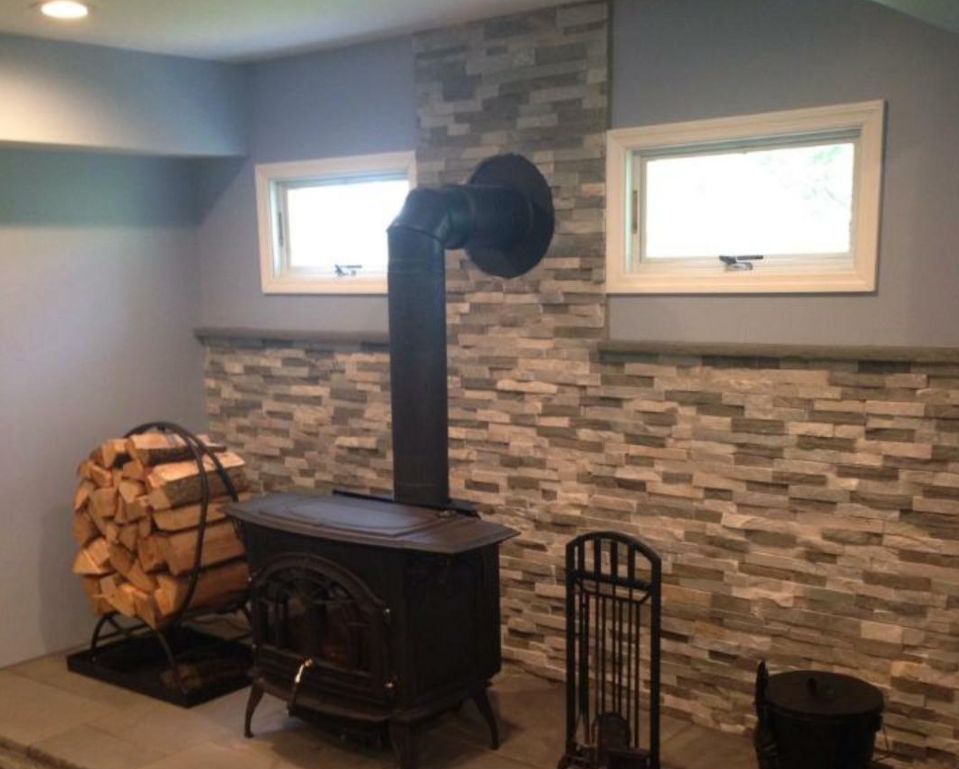 A wood stove is sitting in a room with a stone wall.