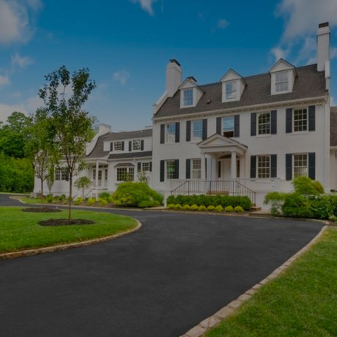 A large white house with black shutters and a black driveway