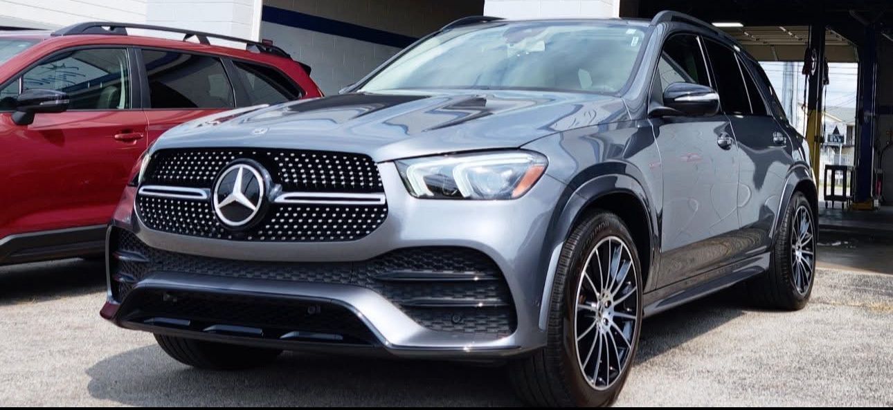 Gray Mercedes SUV in a car lot with a red SUV partially visible.