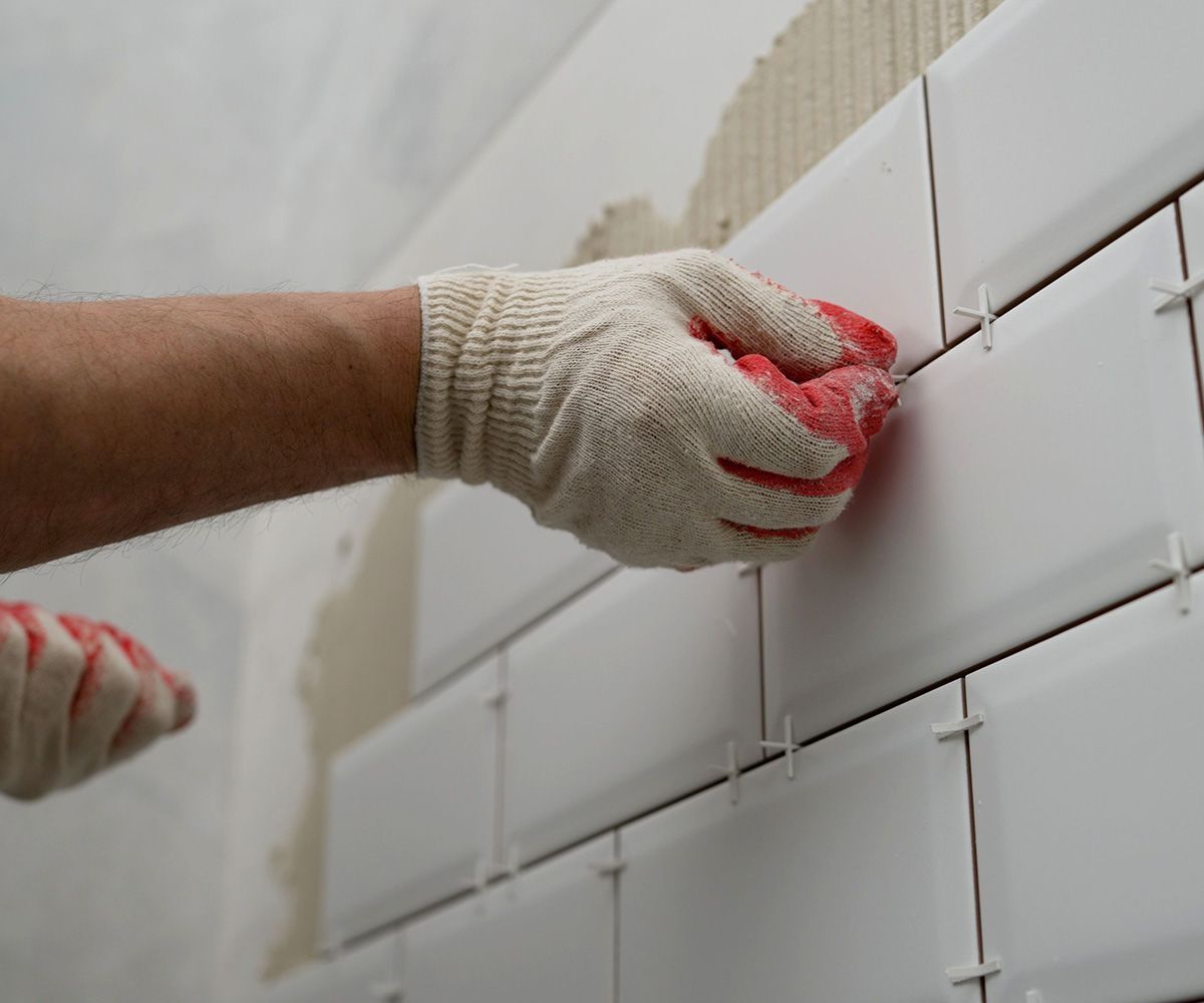 Worker Lay Ceramic Tiles on the Kitchen Wall — Omaha, NE — Lewis Tile Installations