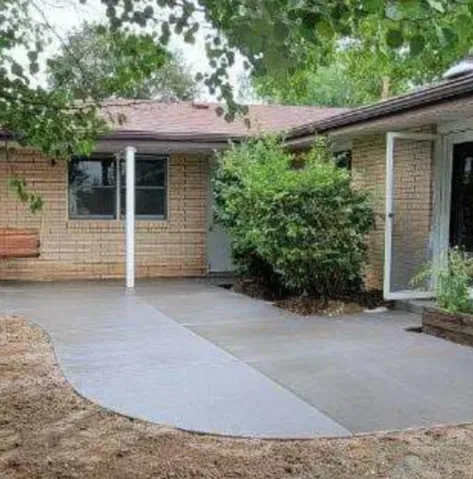 Brick house with a curved concrete walkway and a bush by the front entrance