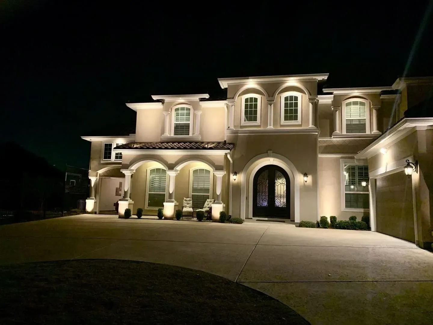 The front of a large house is lit up at night.