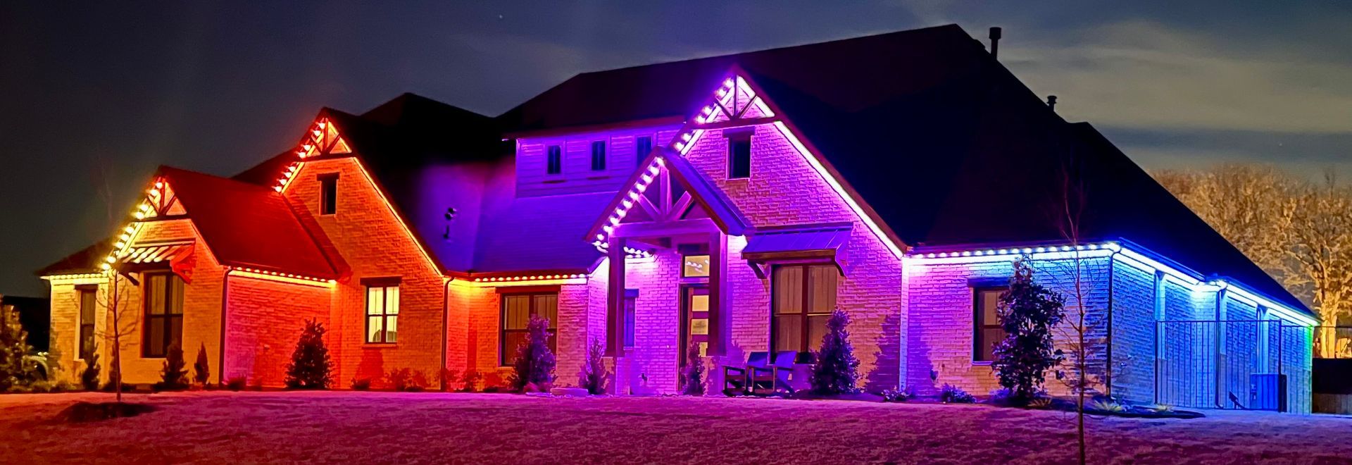 A large house is decorated with purple and blue christmas lights.