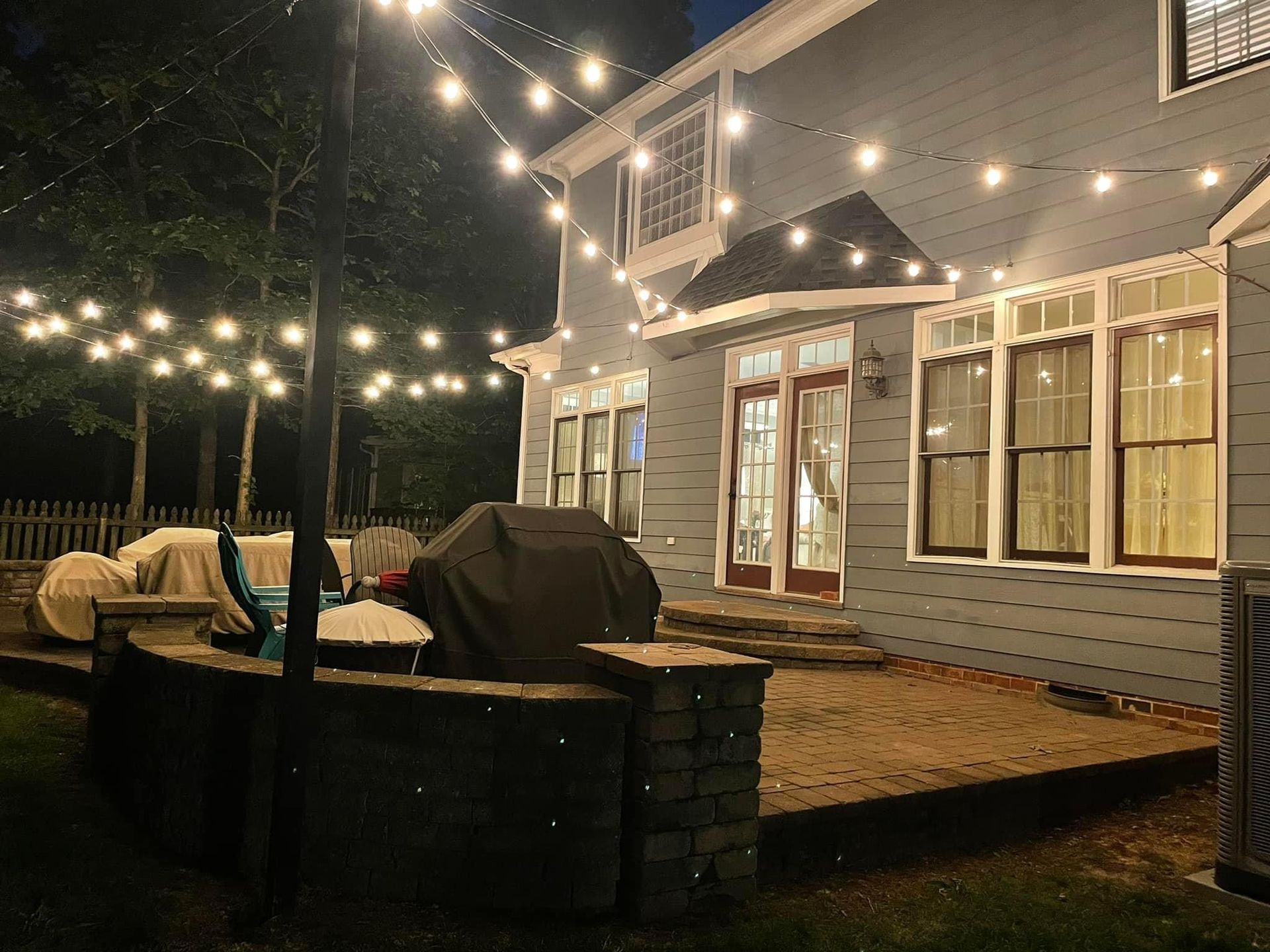 A house with a grill and string lights on it at night.