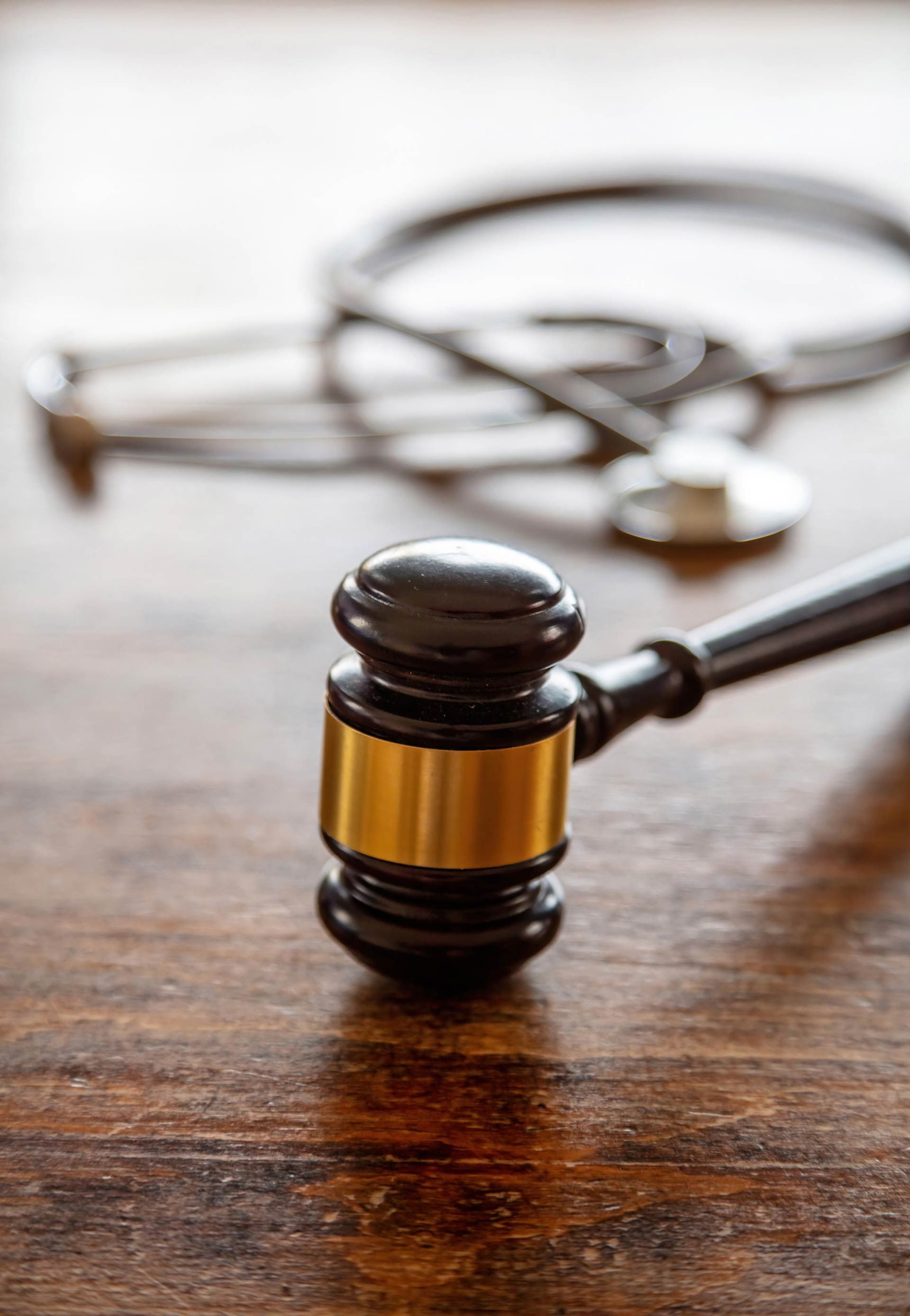 A judge's gavel on a wooden table next to a stethoscope