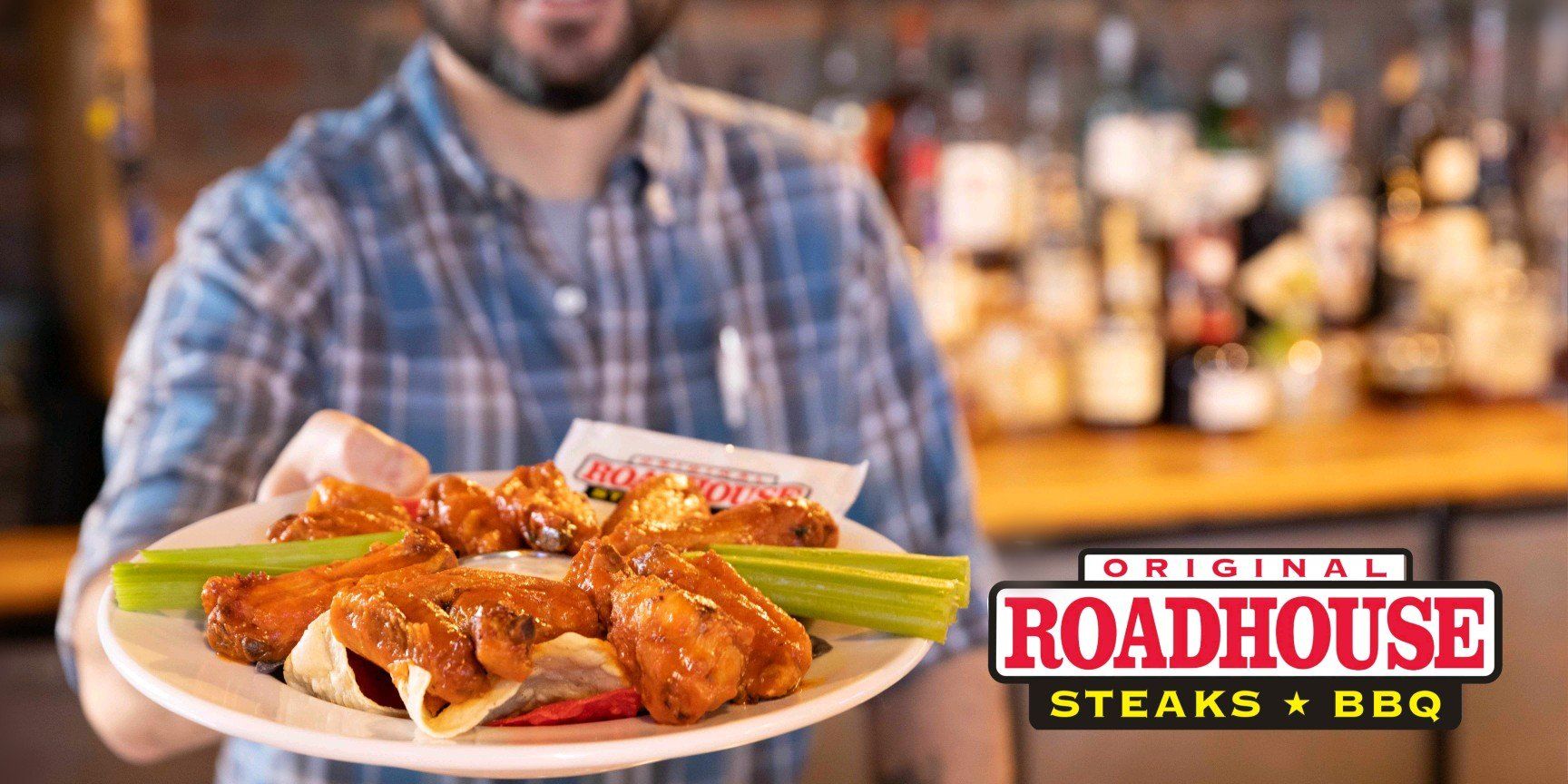 A man is holding a plate of chicken wings and celery.