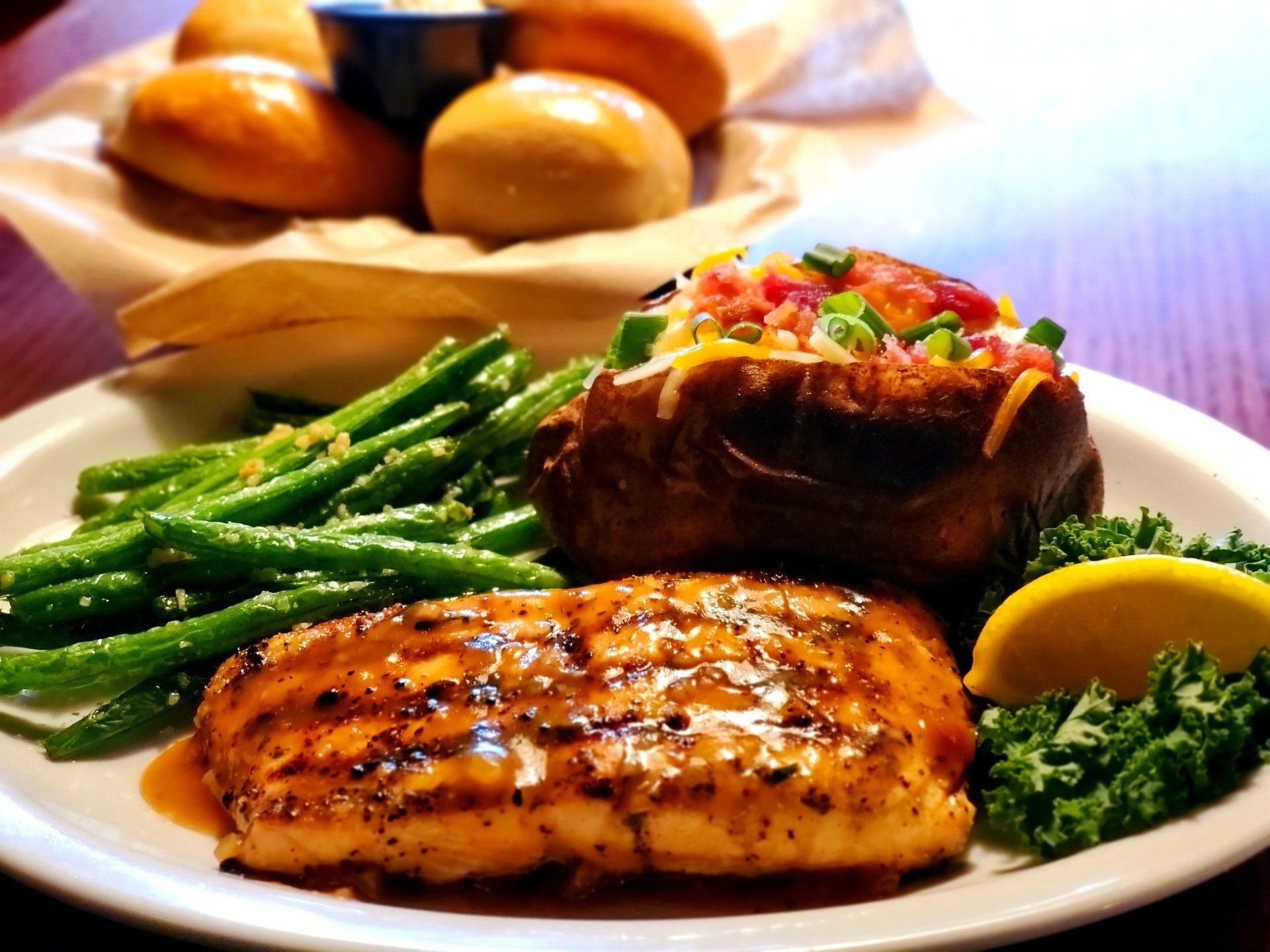 A plate of food with green beans and a baked potato