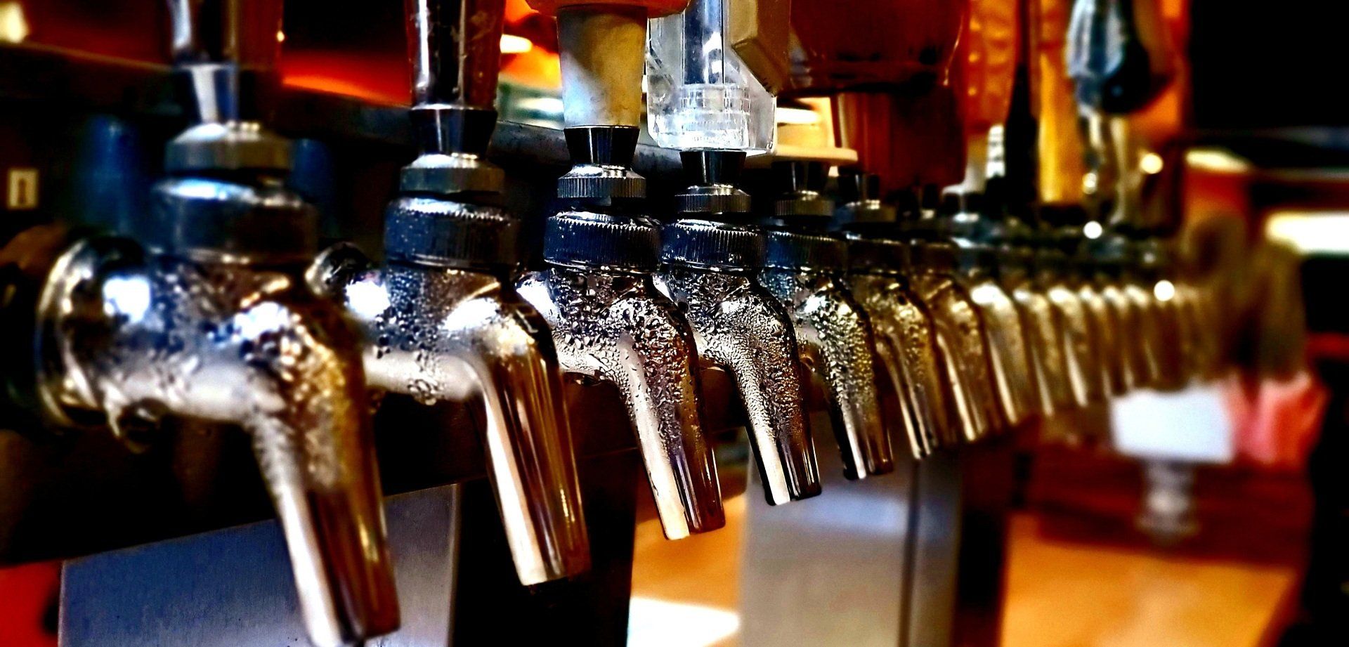A row of beer taps are lined up on a bar.
