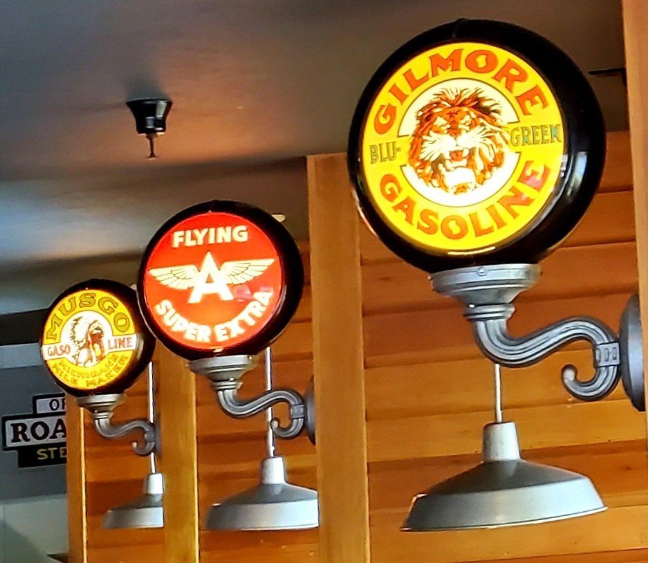 A sign for gilmore gasoline hangs on a wooden wall