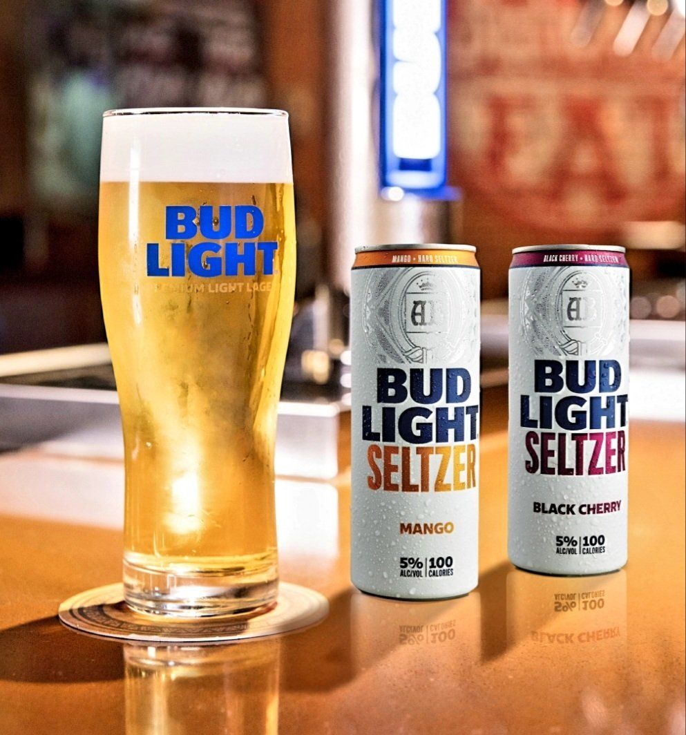 A glass of bud light next to two cans of bud light seltzer