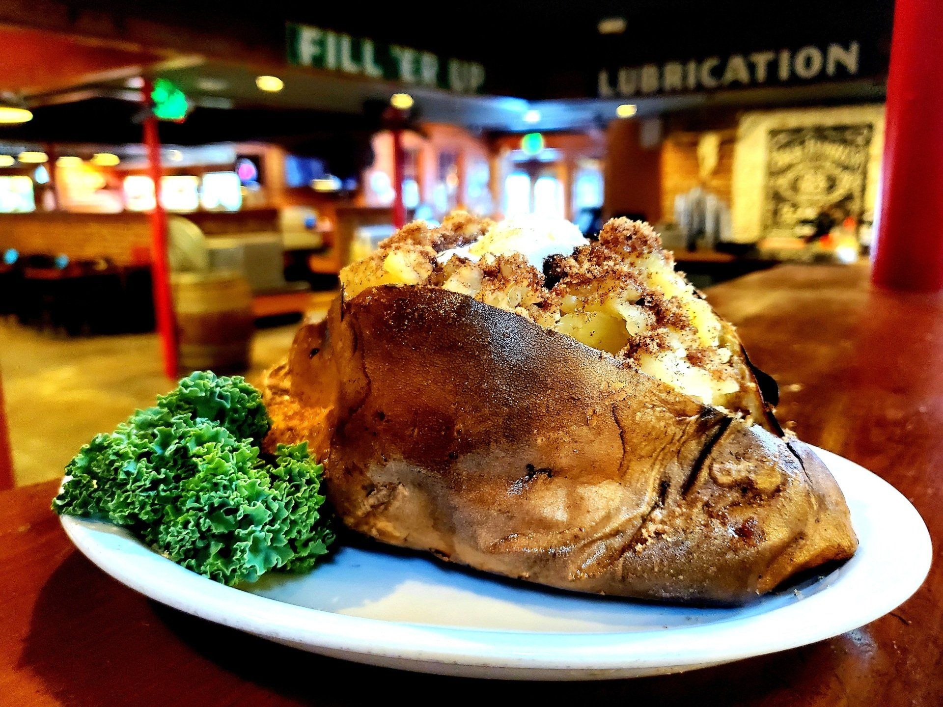 A baked potato is sitting on a white plate on a table.