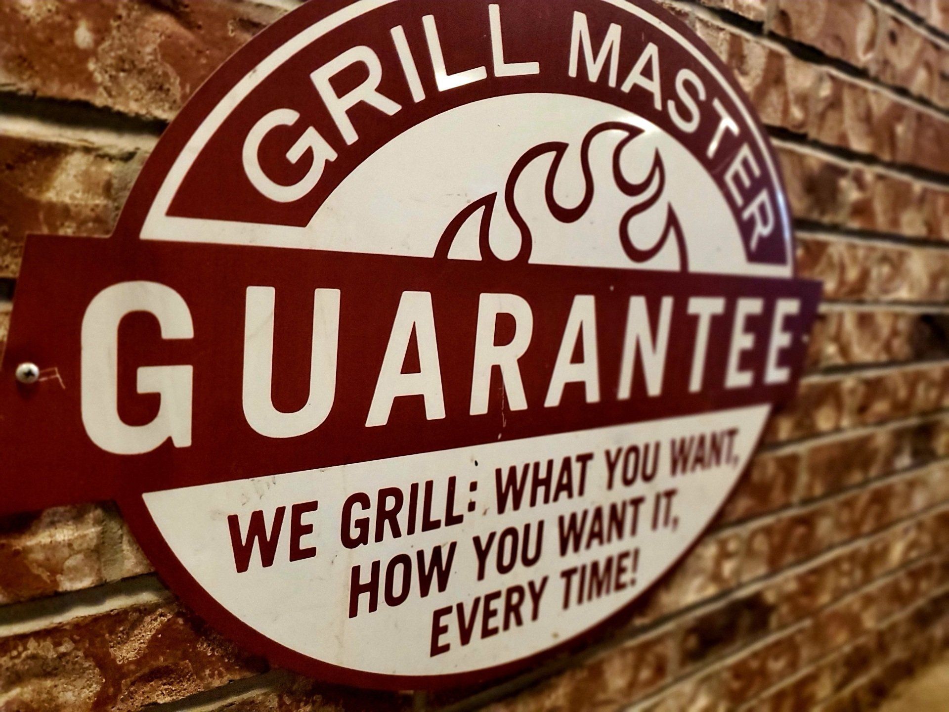 A sign on a brick wall that says grill master guarantee