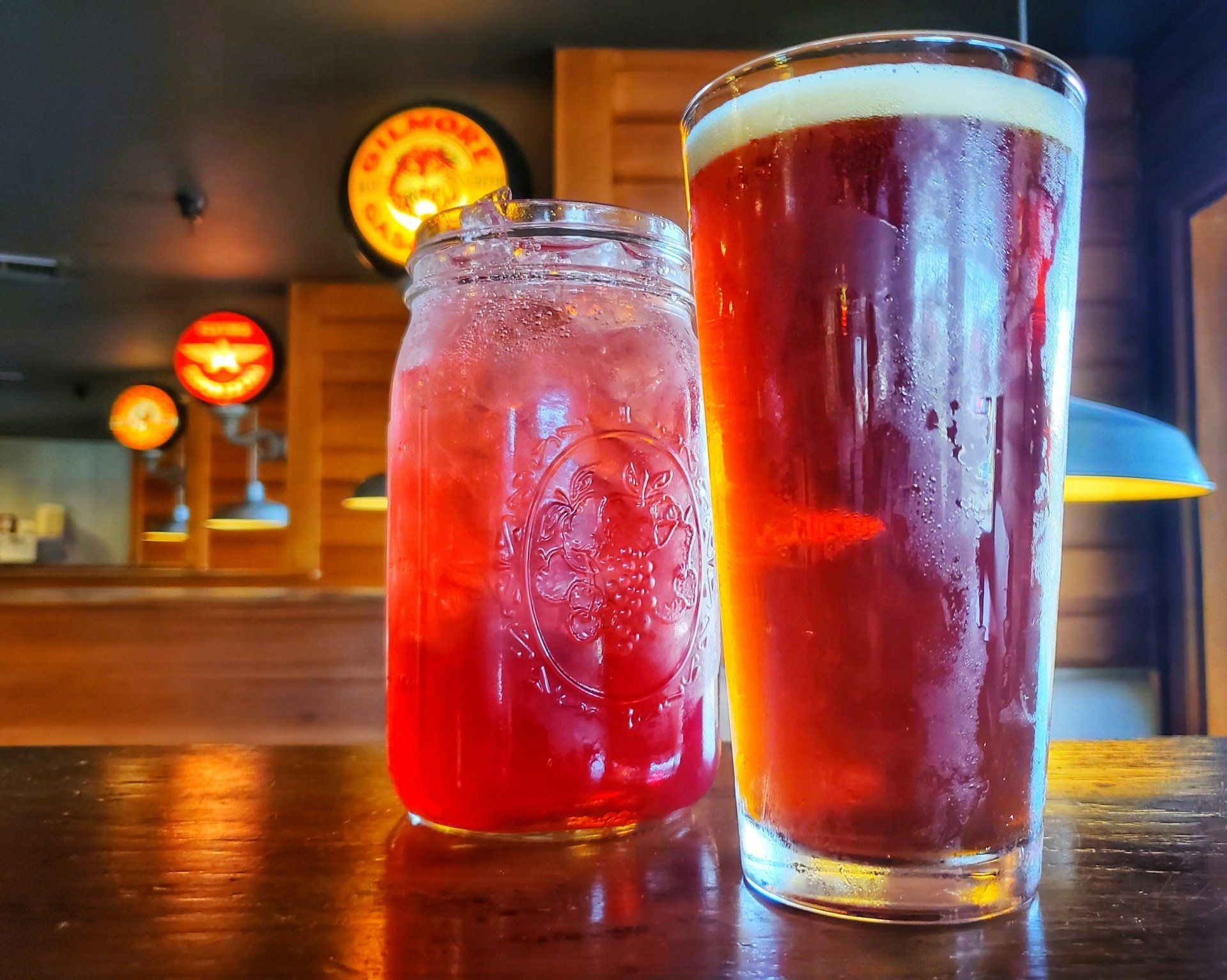 Two glasses of beer and a jar of juice are on a table.