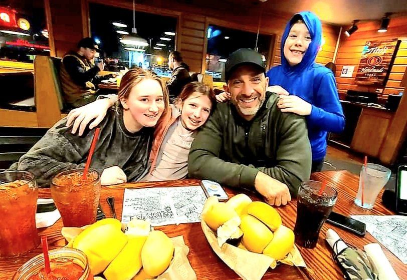 A man and three children are sitting at a table in a restaurant.