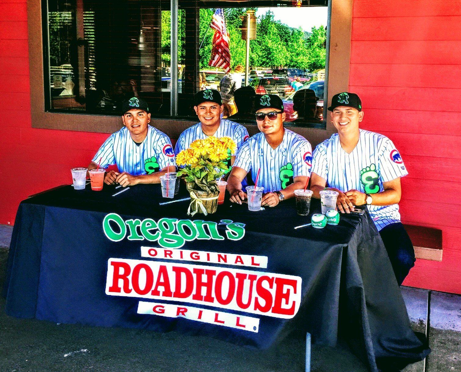 A group of men sitting at a table with a sign that says oregon 's original roadhouse grill