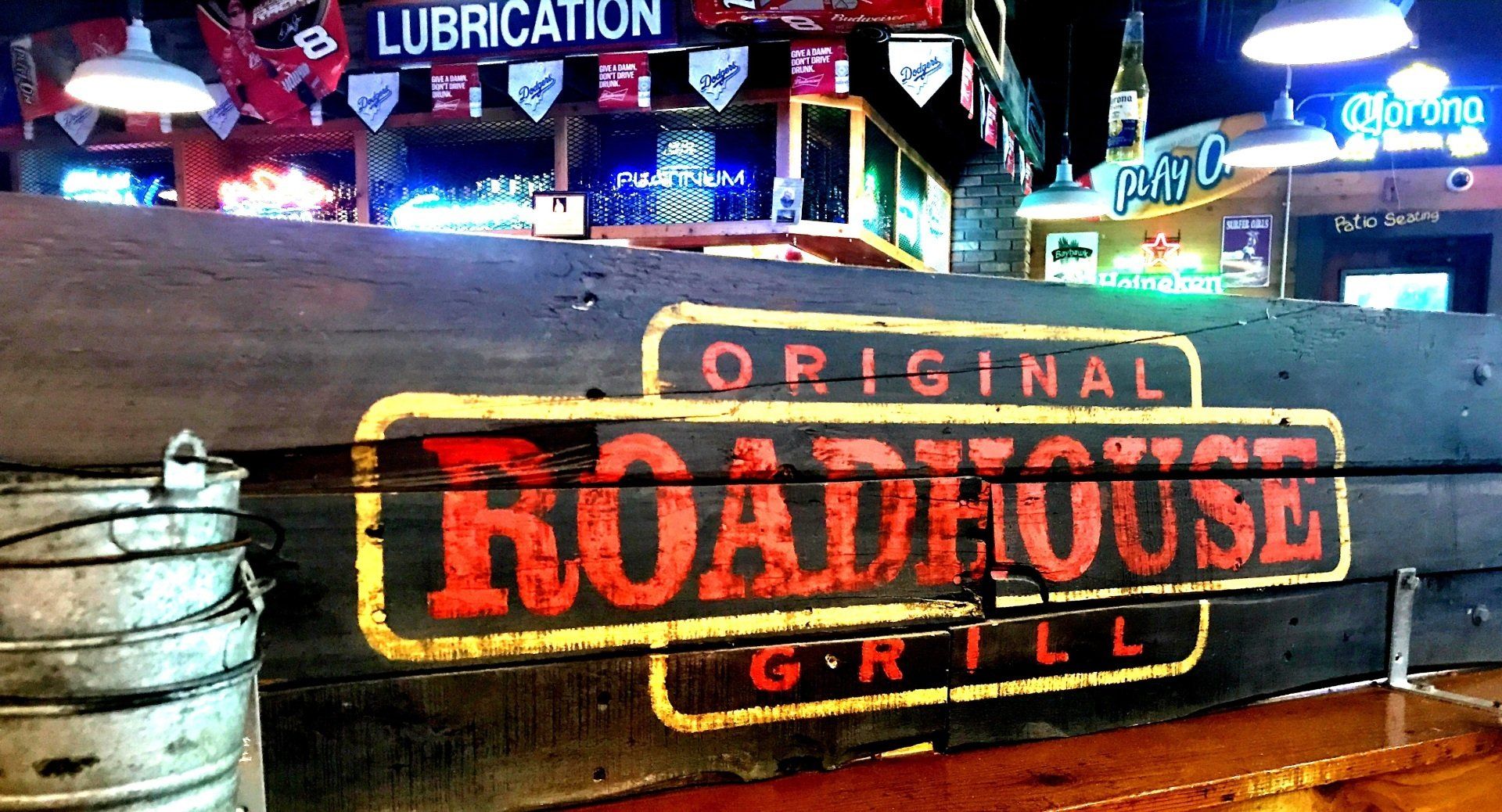 A roadhouse grill sign is painted on a wooden wall