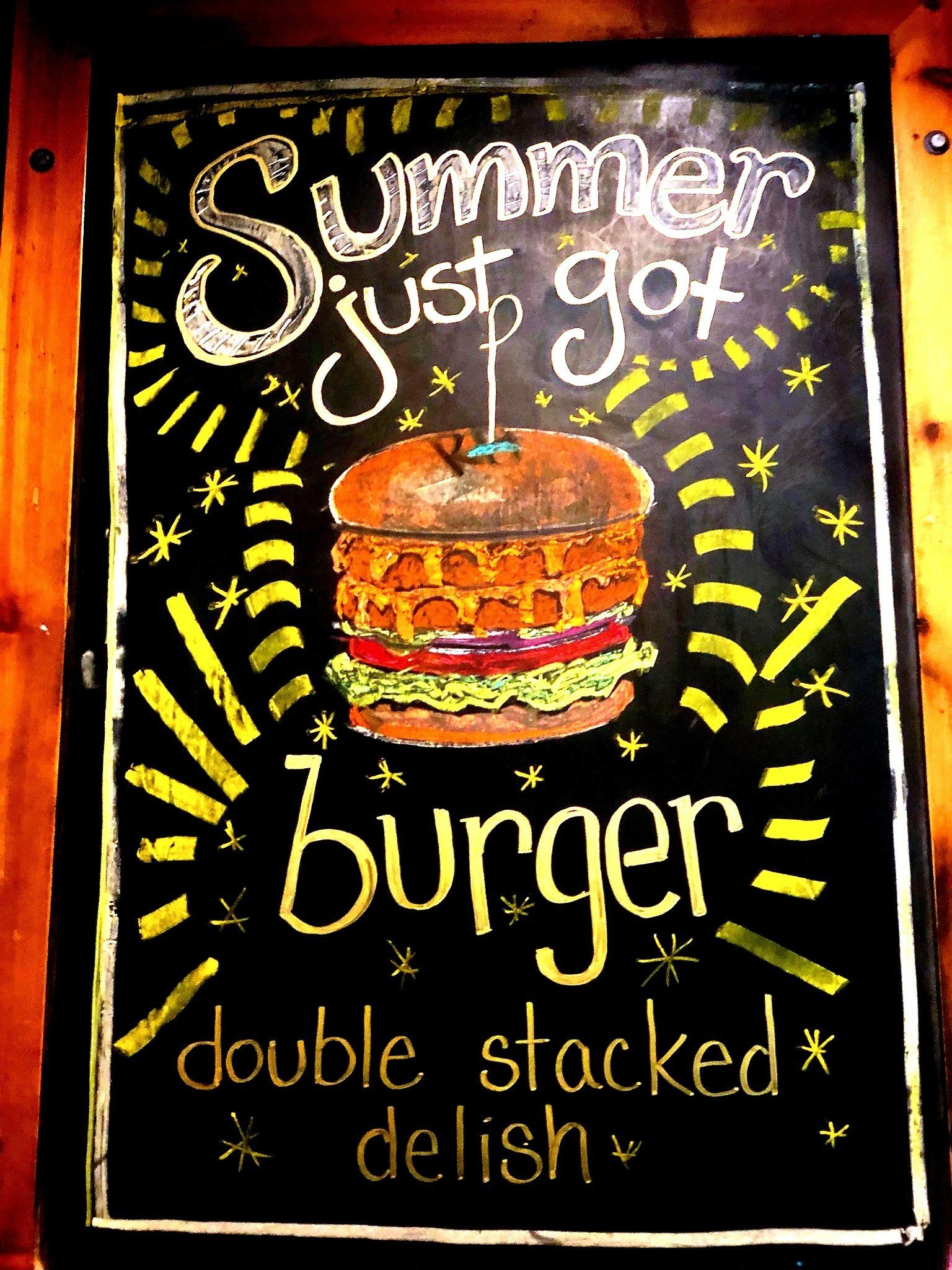A sign that says summer just got burger double stacked delish