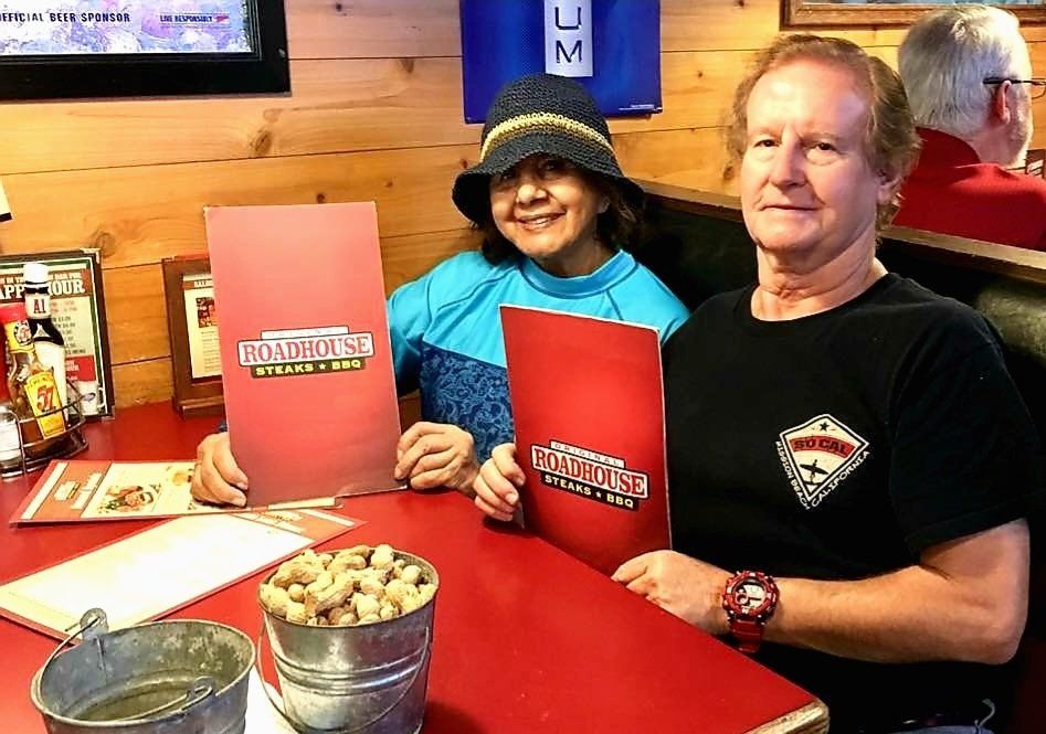 A man and a woman are sitting at a table holding menus