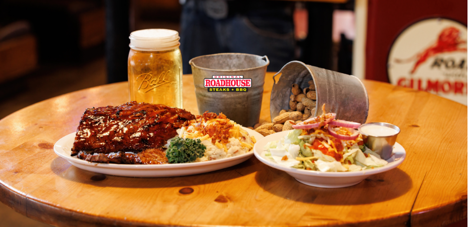 A wooden table topped with plates of food and a glass of beer.