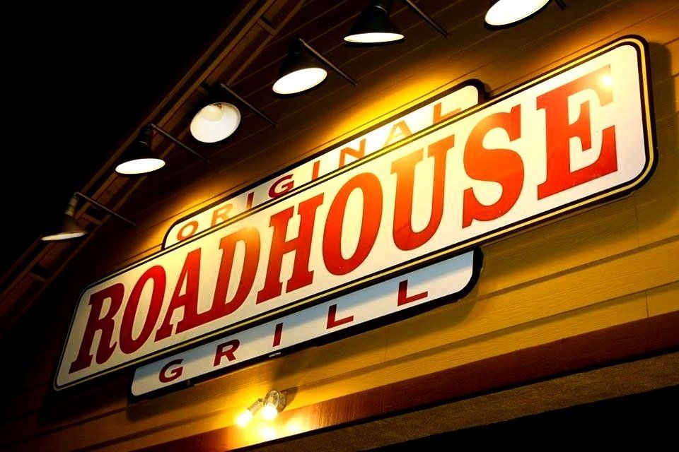 A sign for the original roadhouse grill hangs on the side of a building