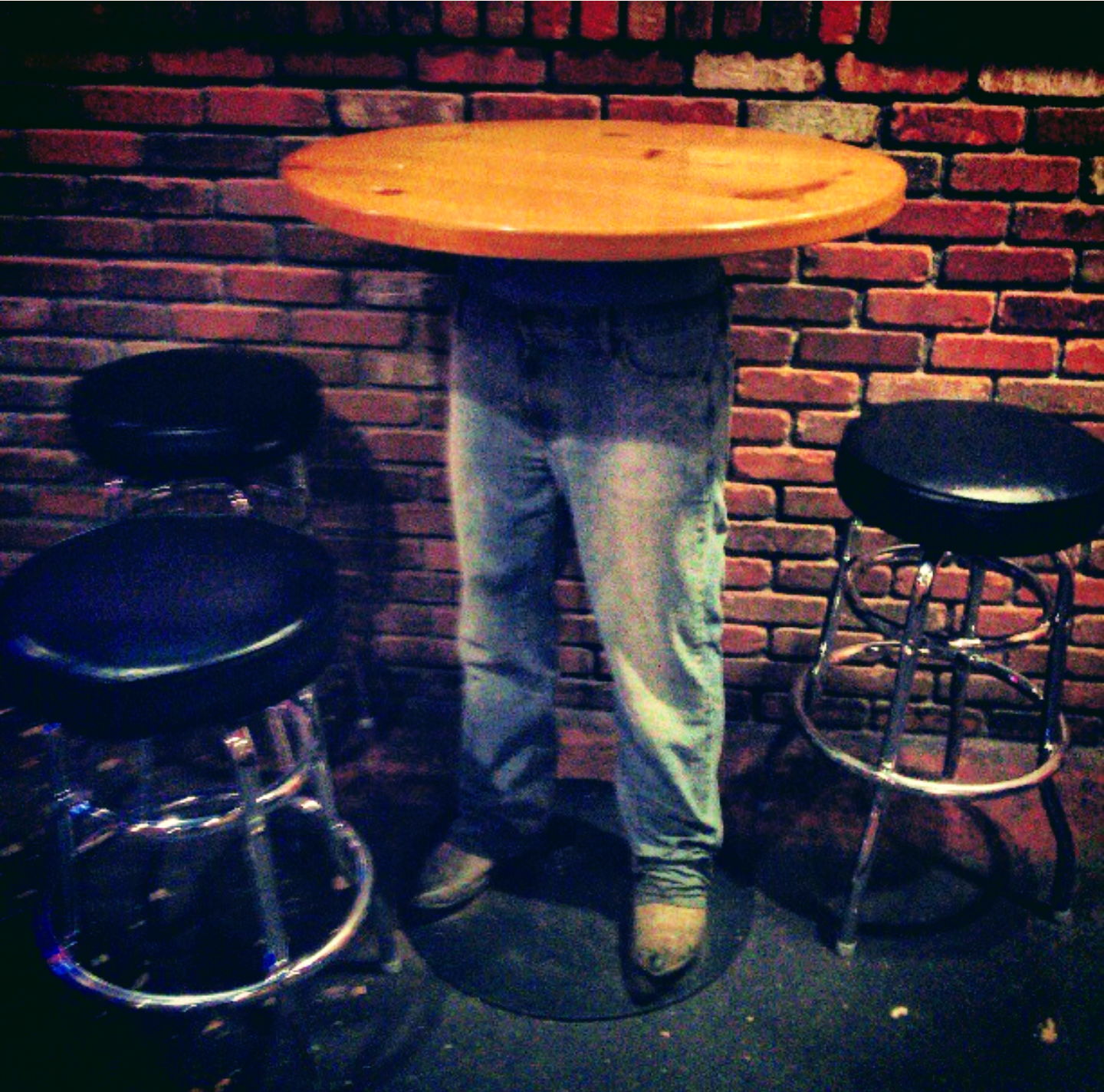 A man 's legs are visible behind a wooden table