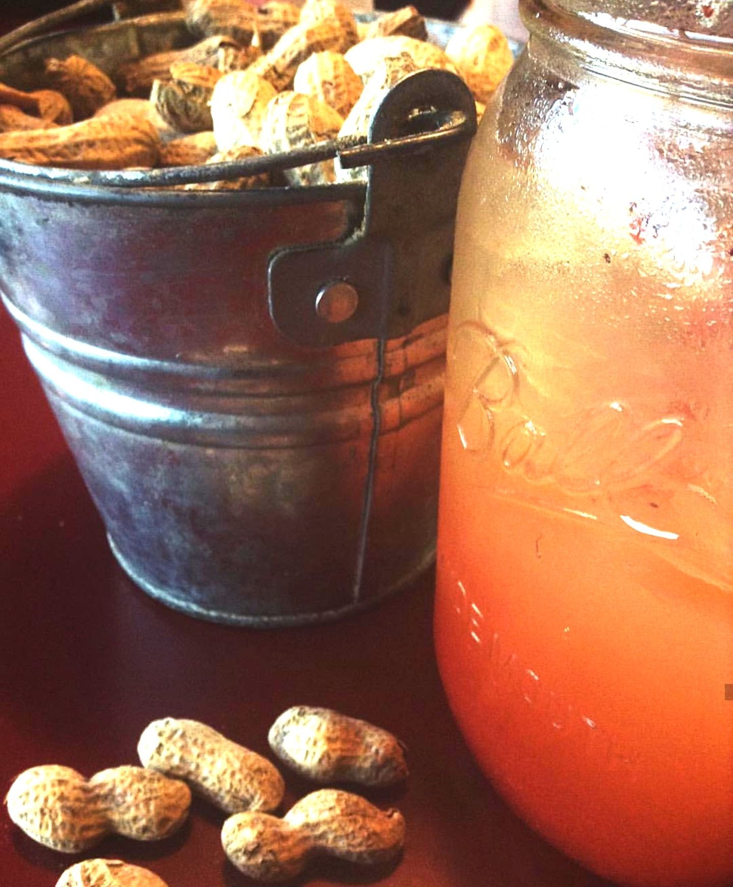 A bucket of peanuts sits next to a jar of sauce