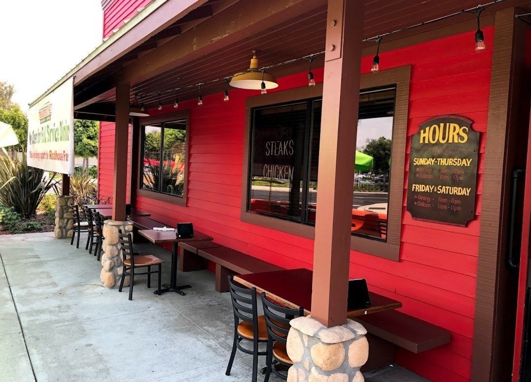 A red building with a sign that says hours on it