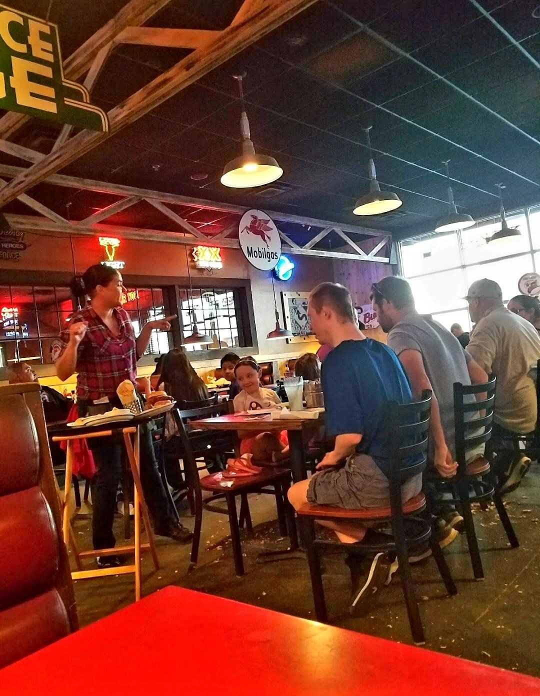 People sitting at tables in a restaurant under a sign that says peace