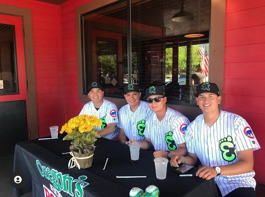 A group of baseball players are sitting at a table