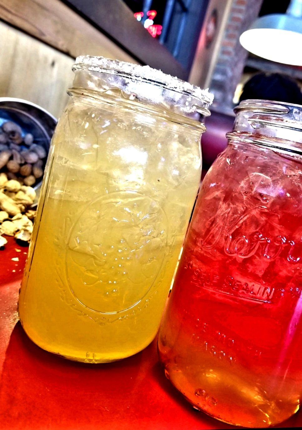 Two mason jars filled with liquid are sitting on a red table.