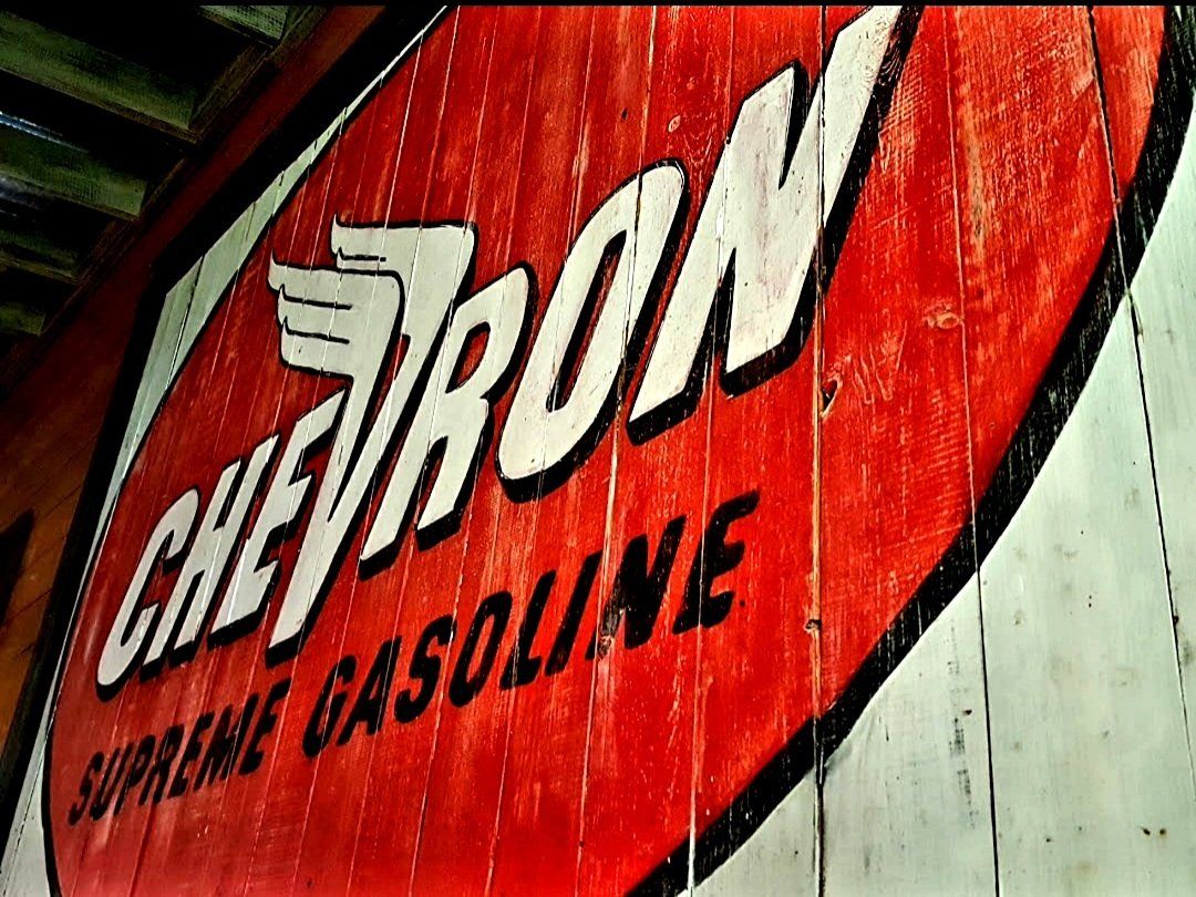 A red sign that says chevron supreme gasoline on it