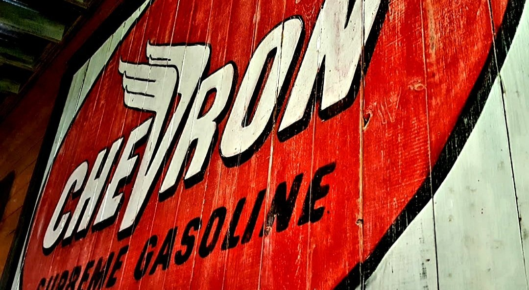 A red sign that says chevron gasoline on it