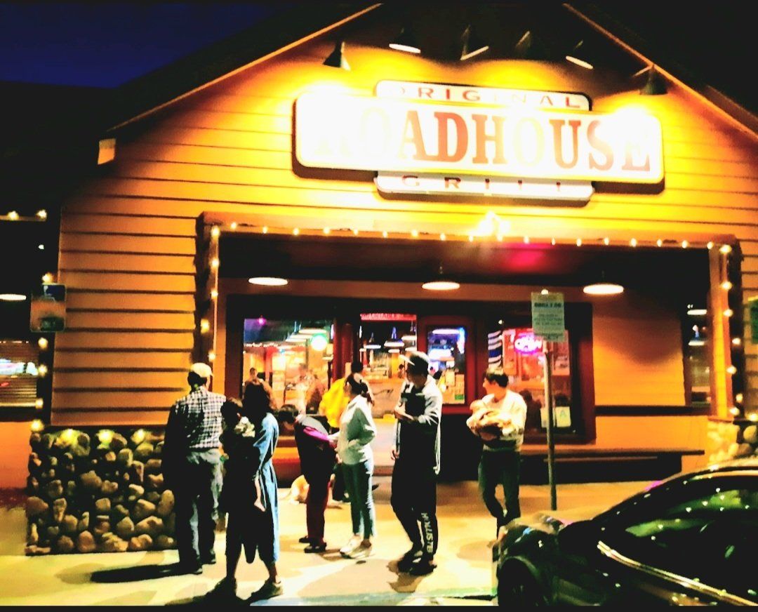 A group of people are standing outside of a restaurant called the hash house