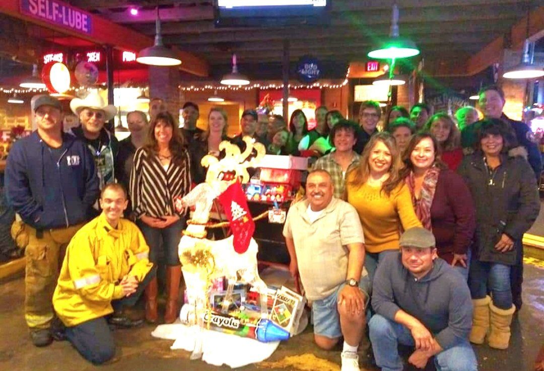 A group of people are posing for a picture in front of a reindeer statue.